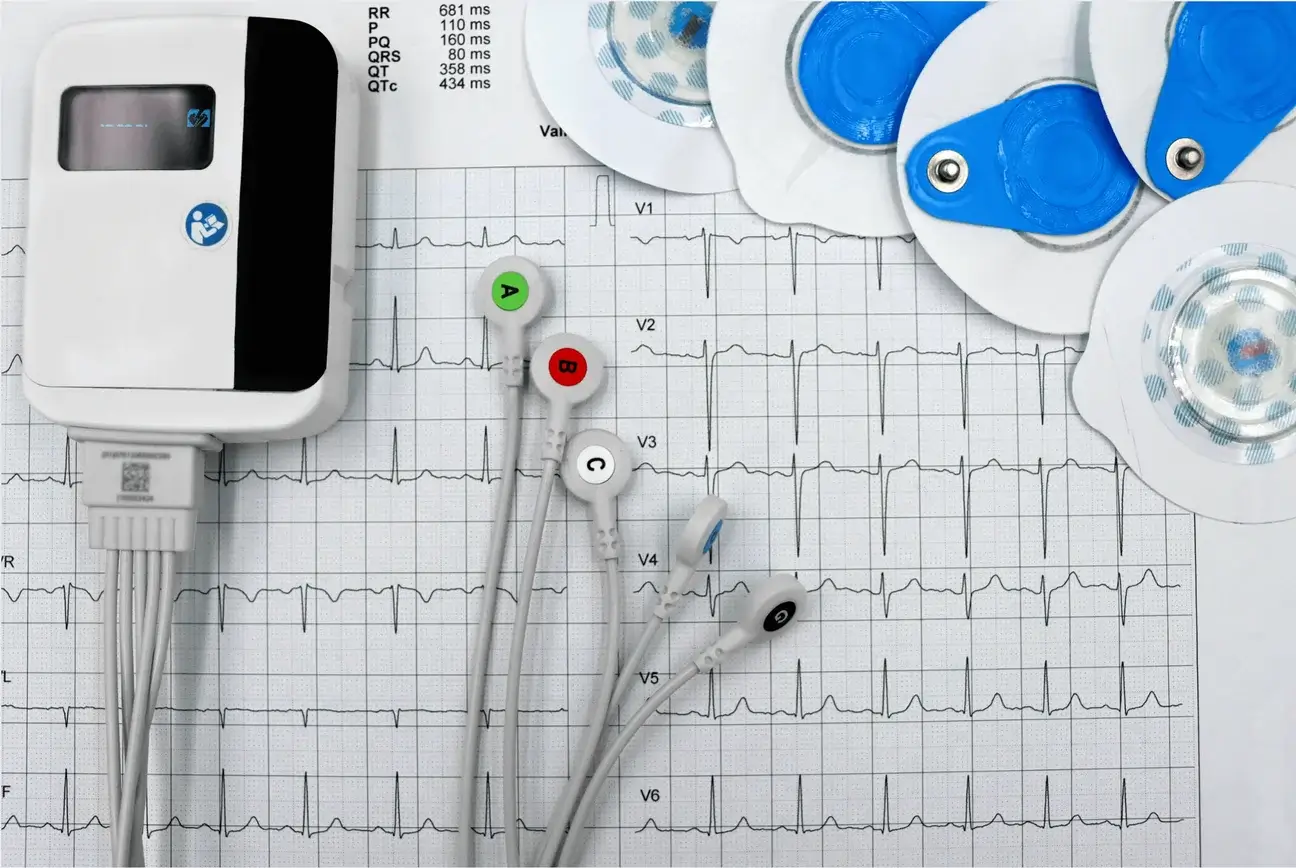 Portable ECG monitor with labeled lead wires and electrodes on a printed ECG trace